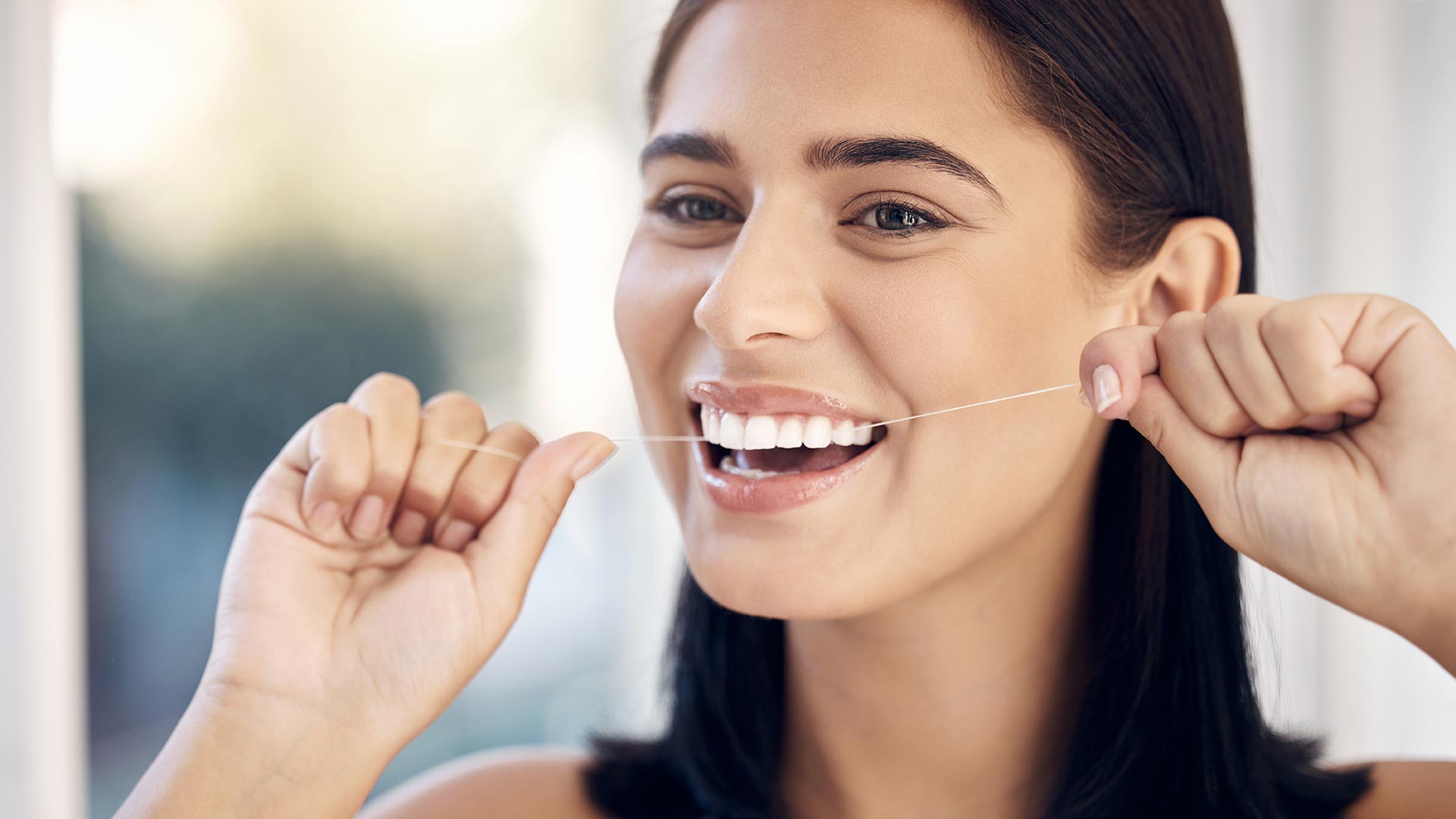 woman smiling and flossing in the morning